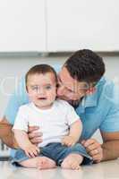 Loving father kissing baby sitting on counter