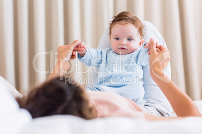 Baby playing with mother in bed