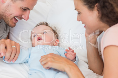 Parents looking at baby boy in bed