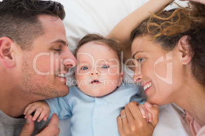 Cute baby with parents in bed