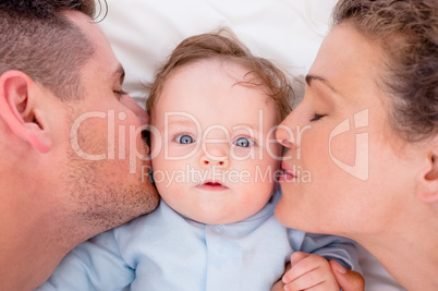 Loving parents kissing baby