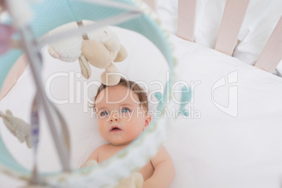 Baby looking at toys hanging in crib