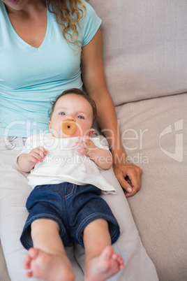 Baby with mother sitting on sofa