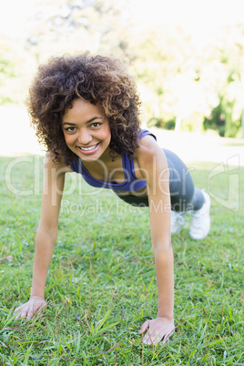Happy woman doing push ups in park