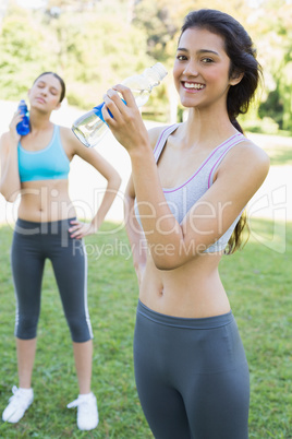 Fit women drinking water in park