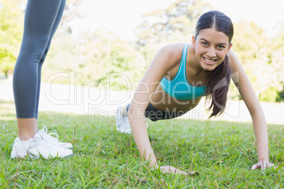 Smiling woman doing push ups in park