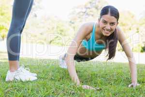 Smiling woman doing push ups in park