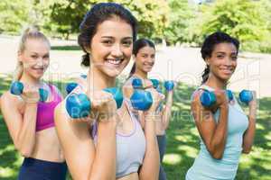 Happy multiethnic women lifting dumbbells
