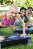 Smiling women doing step aerobics