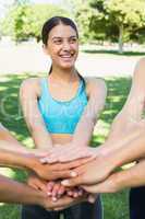 Smiling sporty woman stacking hands with friends