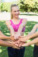 Fit woman stacking hands with friends