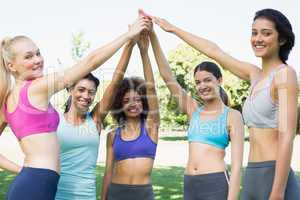Women in sportswear raising hands in park
