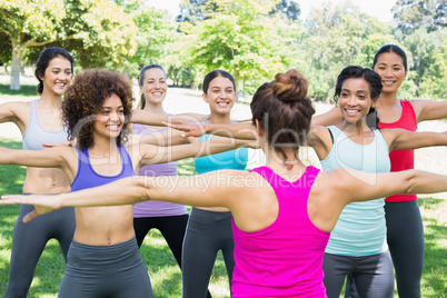 Women exercising with instructor at park