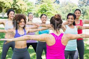 Women exercising with instructor at park