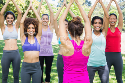 Smiling women exercising with instructor at park