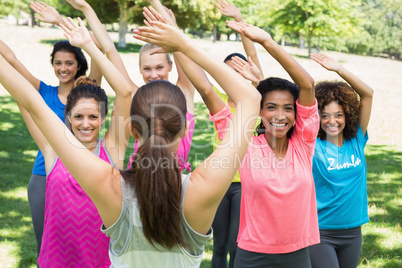 Women performing fitness dance with instructor at park