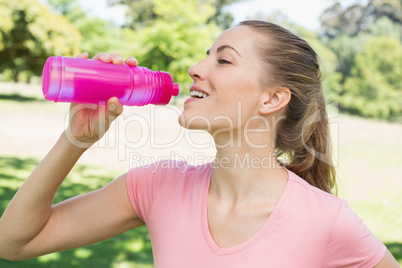 Sporty woman drinking water at park