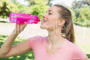 Sporty woman drinking water at park