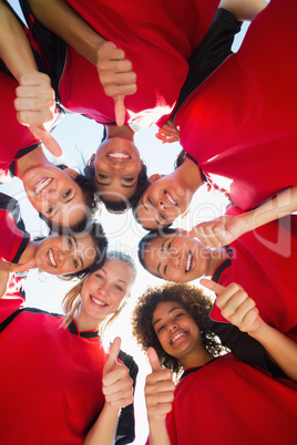 Soccer team gesturing thumbs up while forming huddle