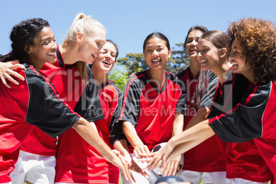 Female soccer team stacking hands