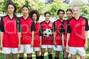 Female soccer team with ball at park