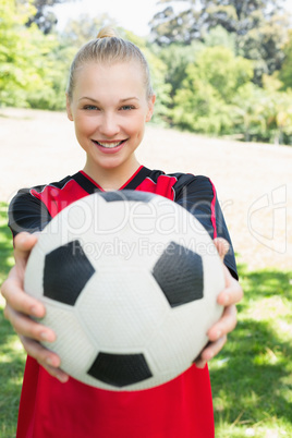 Beautiful soccer player showing ball at park