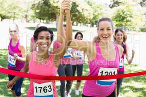 Breast cancer participants crossing finish line at race