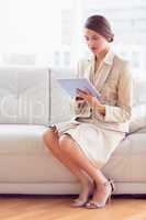 Pretty businesswoman sitting on sofa using tablet pc