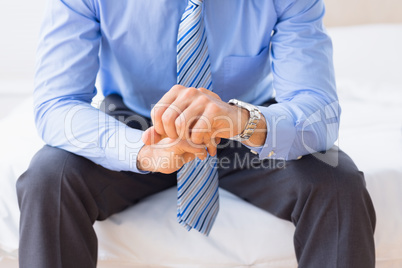 Businessman sitting on bed checking the time