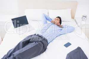 Relaxed businessman lying on his bed