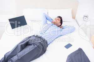 Smiling businessman lying on his bed