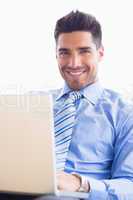 Happy businessman on couch using his laptop