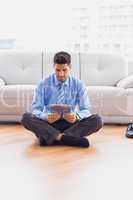 Businessman sitting on the floor using tablet