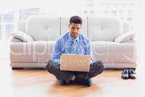 Businessman sitting on floor using laptop