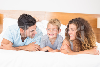 Happy young family lying on bed looking at each other