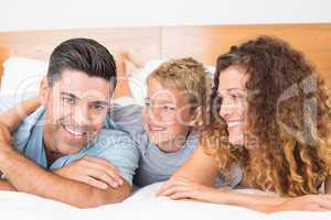 Smiling young family lying on bed together