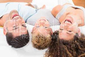 Laughing young family lying on bed together