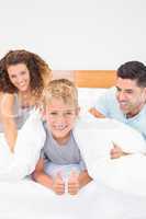 Cute young family messing about on bed