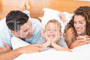 Cute young family lying on bed together smiling
