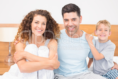 Happy young family smiling at camera on bed