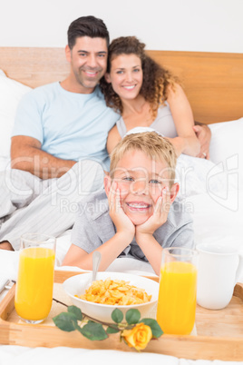 Smiling young family having breakfast in bed