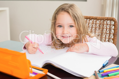 Happy little girl colouring at the table