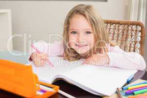 Happy little girl colouring at the table