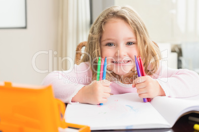 Cheerful little girl colouring at the table