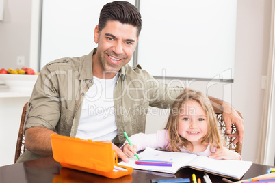 Happy little girl colouring at the table with her father