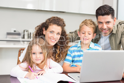 Happy parents colouring and using laptop with their children