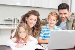 Happy parents colouring and using laptop with their children