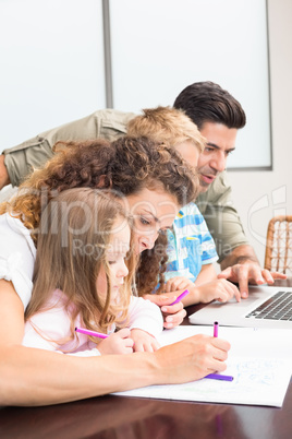 Attractive parents colouring and using laptop with their childre