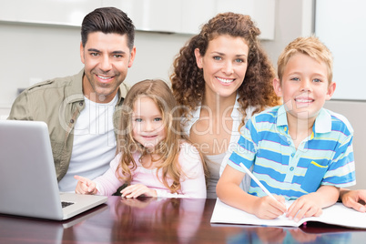 Happy parents colouring and using laptop with their young childr