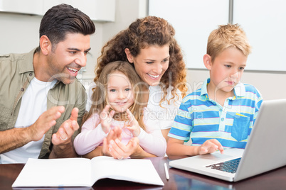 Happy parents using laptop with their young children